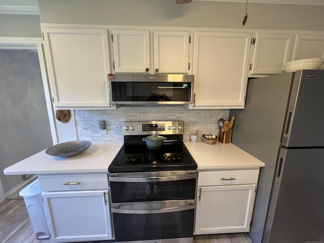 kitchen featuring appliances with stainless steel finishes, white cabinets, light countertops, and backsplash