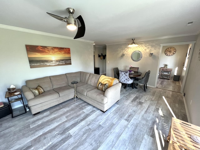 living area featuring a ceiling fan, wood finished floors, ornamental molding, and baseboards