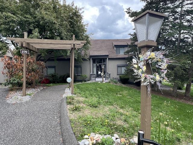 view of front of property with a front lawn, a shingled roof, and a pergola