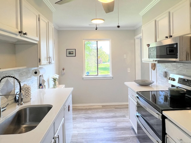 kitchen featuring appliances with stainless steel finishes, a sink, decorative backsplash, crown molding, and light countertops
