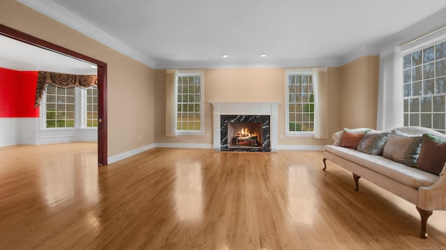 living room featuring a wealth of natural light, light hardwood / wood-style floors, crown molding, and a high end fireplace