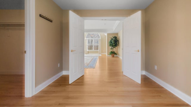 corridor with baseboards and light wood finished floors