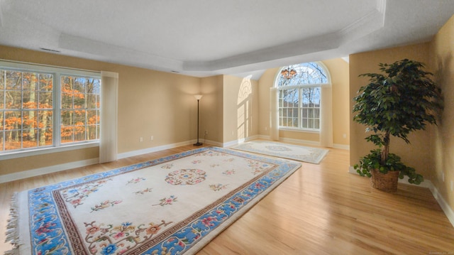 interior space with wood finished floors, baseboards, visible vents, crown molding, and a tray ceiling