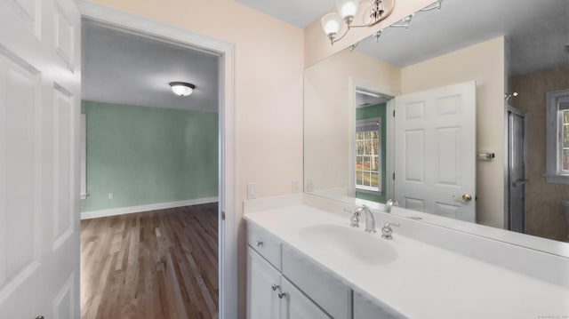 bathroom with vanity, baseboards, wood finished floors, and a healthy amount of sunlight