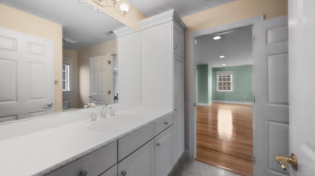 bathroom featuring toilet, vanity, recessed lighting, and baseboards