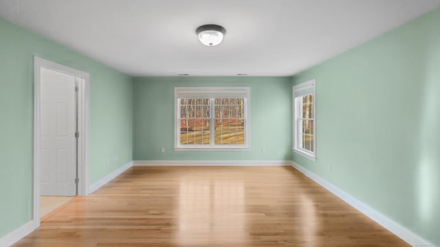 unfurnished room with baseboards and light wood-style floors