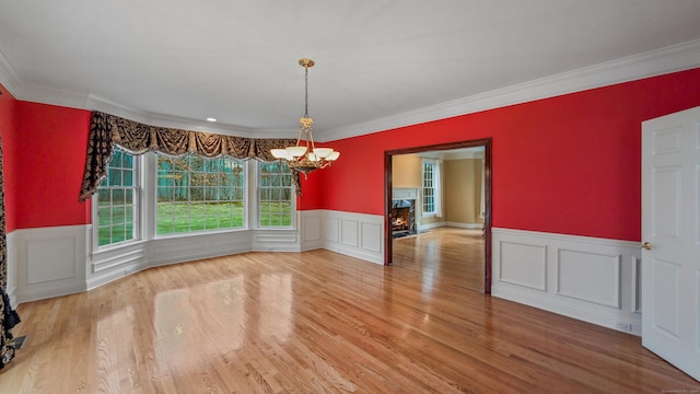 unfurnished dining area featuring a chandelier, wood-type flooring, and ornamental molding