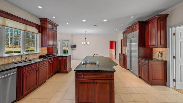 kitchen featuring pendant lighting, stainless steel appliances, a kitchen island with sink, and sink