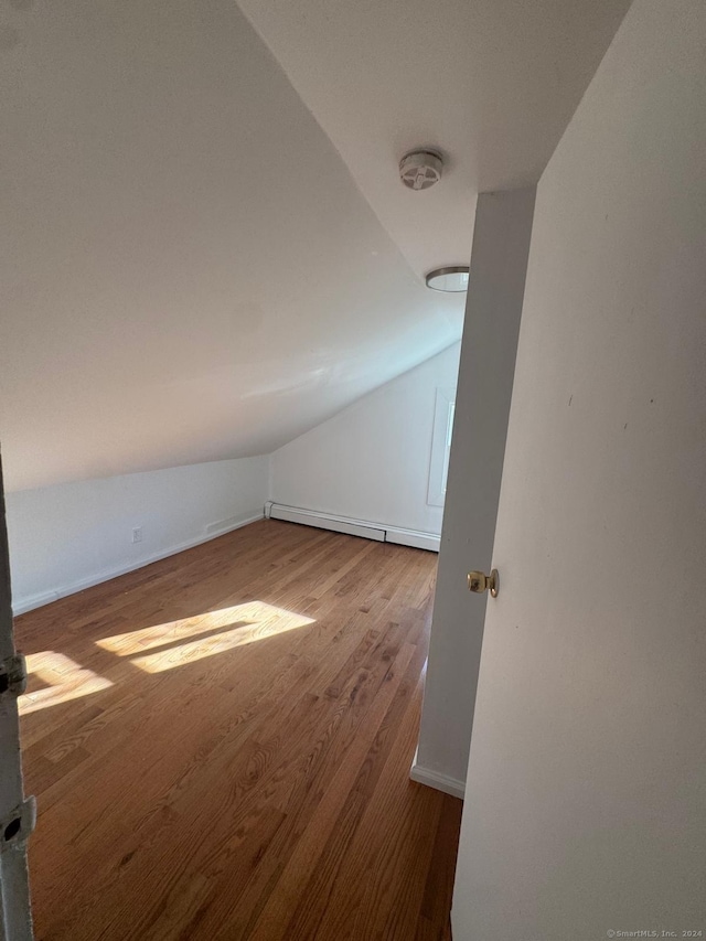 additional living space with hardwood / wood-style floors, a baseboard heating unit, and vaulted ceiling