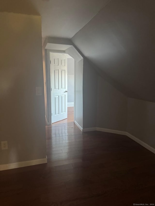 additional living space featuring vaulted ceiling and dark wood-type flooring