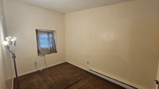 empty room featuring dark carpet and baseboard heating