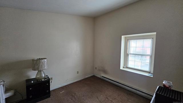 spare room with dark colored carpet and a baseboard heating unit