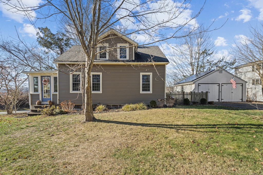 back of property featuring an outbuilding, a garage, and a lawn