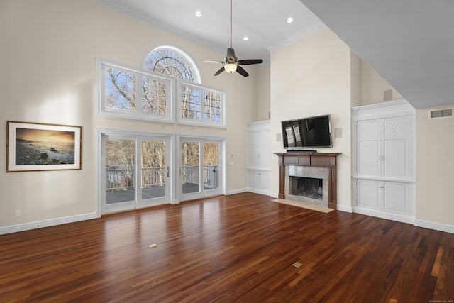 unfurnished living room featuring a premium fireplace, plenty of natural light, wood-type flooring, and a high ceiling