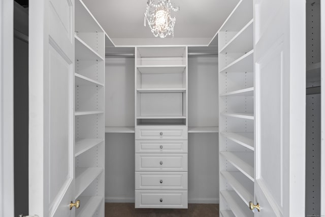 spacious closet with dark carpet and a notable chandelier