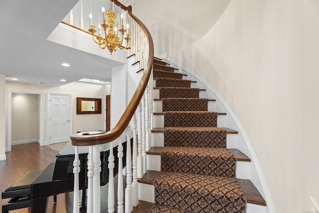 staircase featuring wood-type flooring and a notable chandelier