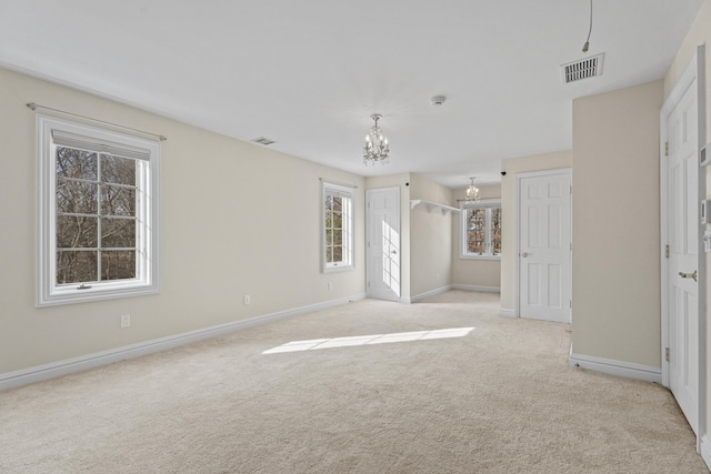 spare room featuring light colored carpet and an inviting chandelier