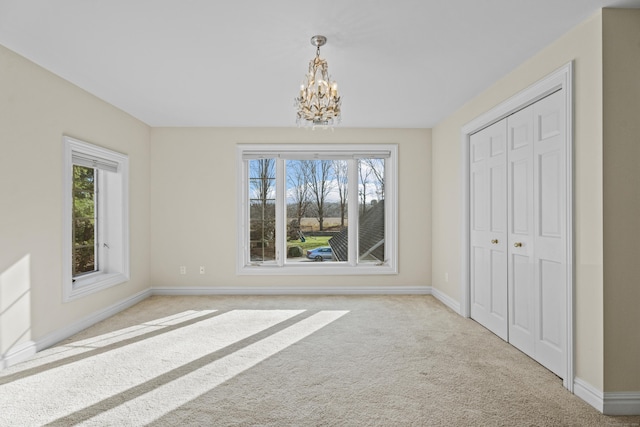 unfurnished dining area featuring plenty of natural light, light colored carpet, and a notable chandelier