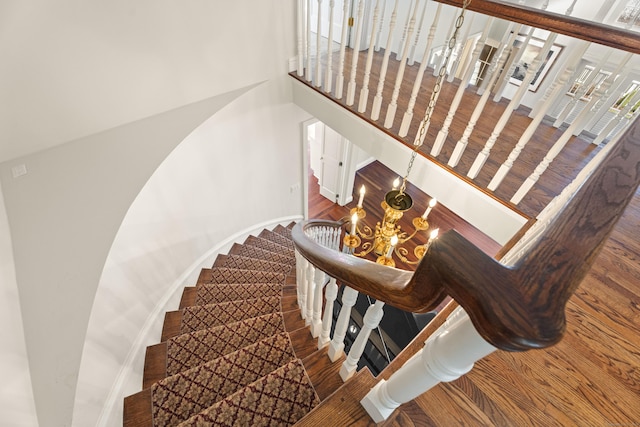 staircase with hardwood / wood-style floors and a notable chandelier