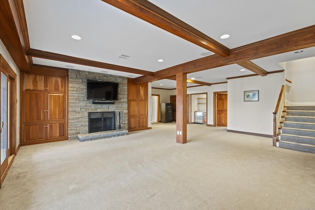 unfurnished living room featuring beam ceiling, a stone fireplace, crown molding, and light colored carpet