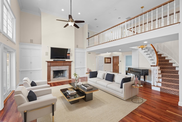 living room featuring a high ceiling, ceiling fan, crown molding, and hardwood / wood-style floors