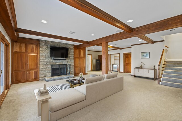 living room featuring beamed ceiling, a fireplace, ornamental molding, and light carpet