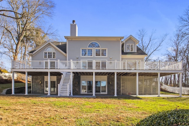 back of property with a wooden deck, a patio, and a lawn