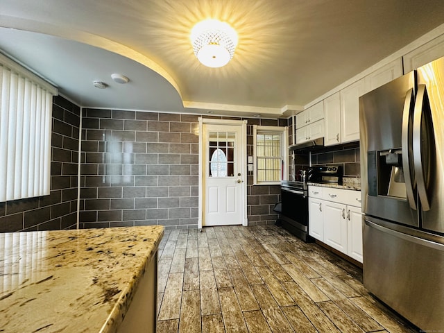 kitchen featuring white cabinets, electric stove, stainless steel fridge, light stone countertops, and dark hardwood / wood-style flooring