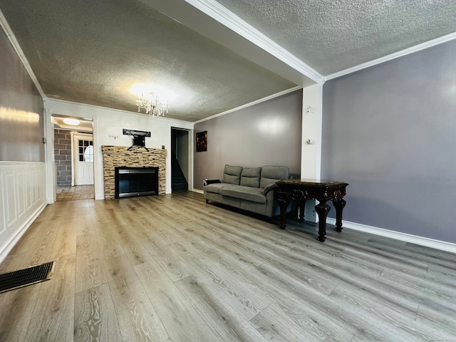 living room featuring a fireplace, a textured ceiling, light hardwood / wood-style floors, and crown molding