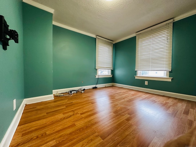 spare room with ornamental molding, a healthy amount of sunlight, a textured ceiling, and wood-type flooring