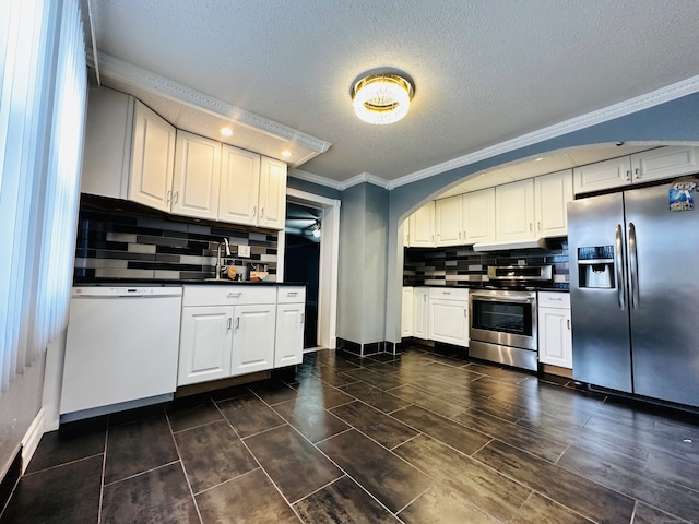 kitchen featuring backsplash, ornamental molding, a textured ceiling, white cabinetry, and stainless steel appliances