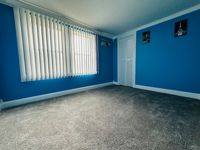 carpeted empty room featuring a textured ceiling and ornamental molding