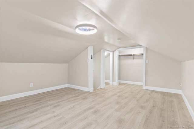 additional living space with light wood-type flooring and vaulted ceiling