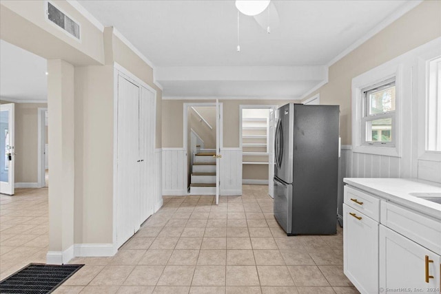 kitchen with white cabinetry, light tile patterned floors, sink, ornamental molding, and stainless steel fridge