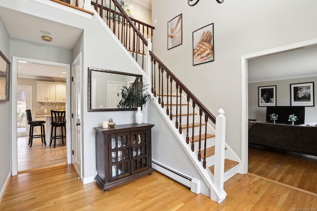 staircase with a baseboard radiator and wood-type flooring