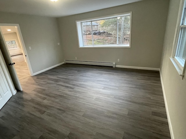 unfurnished room with a baseboard heating unit and dark hardwood / wood-style floors