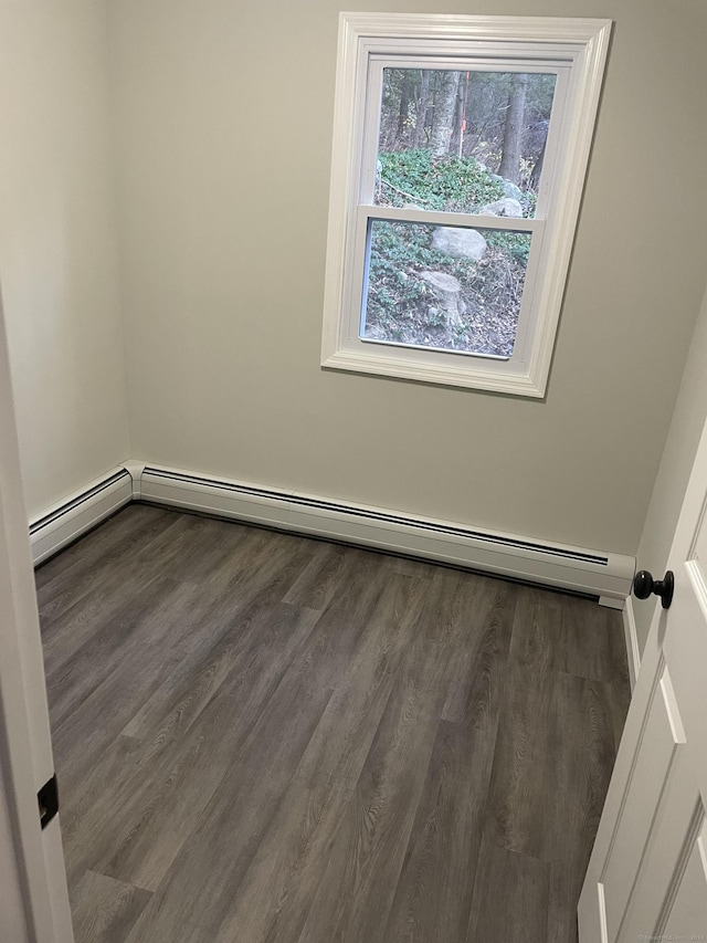 empty room with dark wood-type flooring and baseboard heating