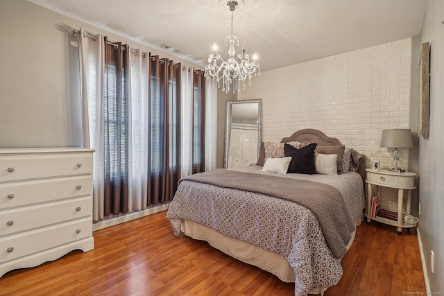 bedroom featuring an inviting chandelier and light hardwood / wood-style flooring