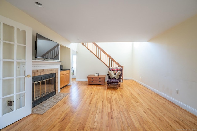 unfurnished living room featuring light wood-type flooring and a tiled fireplace