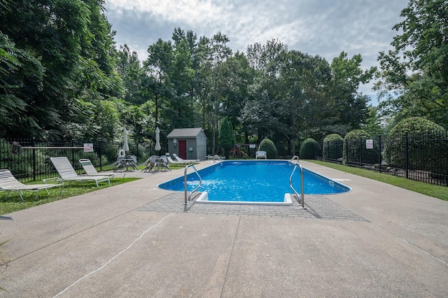 view of pool with a patio and a shed