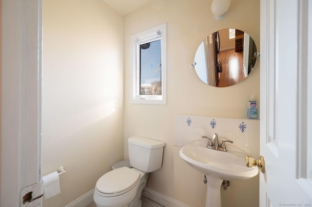 bathroom with backsplash, sink, and toilet