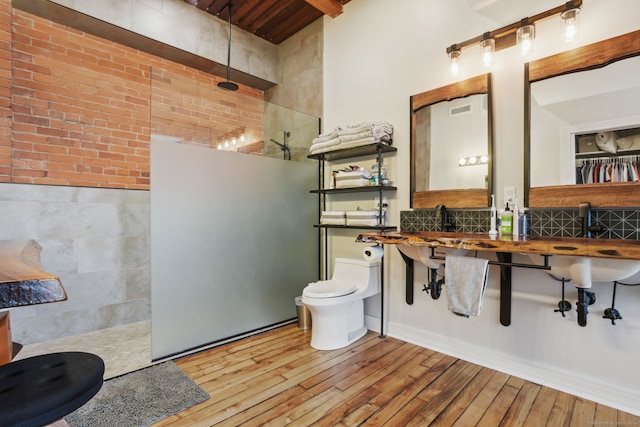 bathroom with hardwood / wood-style flooring, toilet, walk in shower, and tile walls