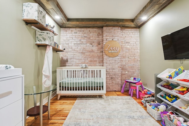 bedroom with light wood-type flooring, brick wall, and a nursery area