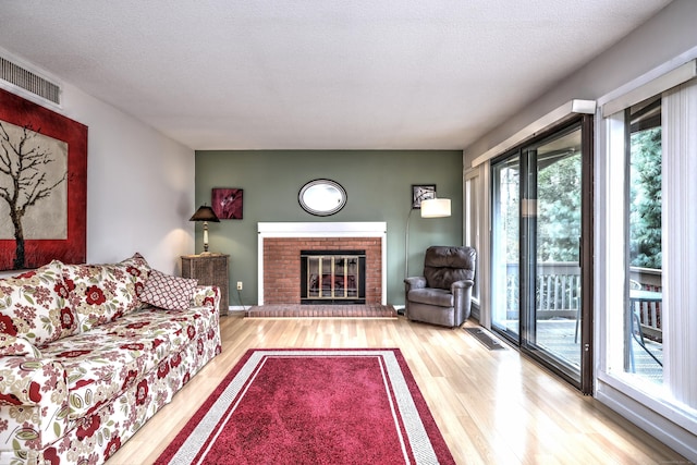 living room with a fireplace, wood-type flooring, and a textured ceiling