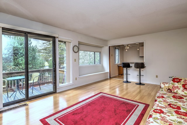 living room featuring wood-type flooring, a textured ceiling, and ceiling fan