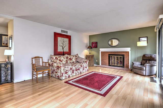 living room with a fireplace, a textured ceiling, and light hardwood / wood-style flooring