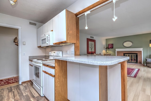 kitchen with a textured ceiling, light hardwood / wood-style flooring, white cabinets, and white appliances