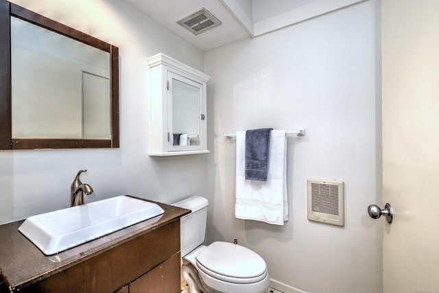 bathroom featuring vanity, heating unit, and toilet