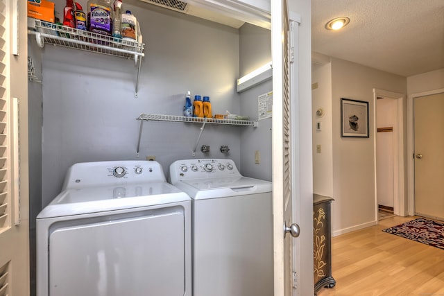 laundry room with light hardwood / wood-style flooring, a textured ceiling, and independent washer and dryer