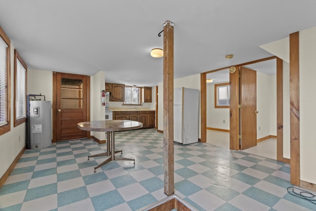 interior space featuring white refrigerator, electric water heater, sink, and a wealth of natural light